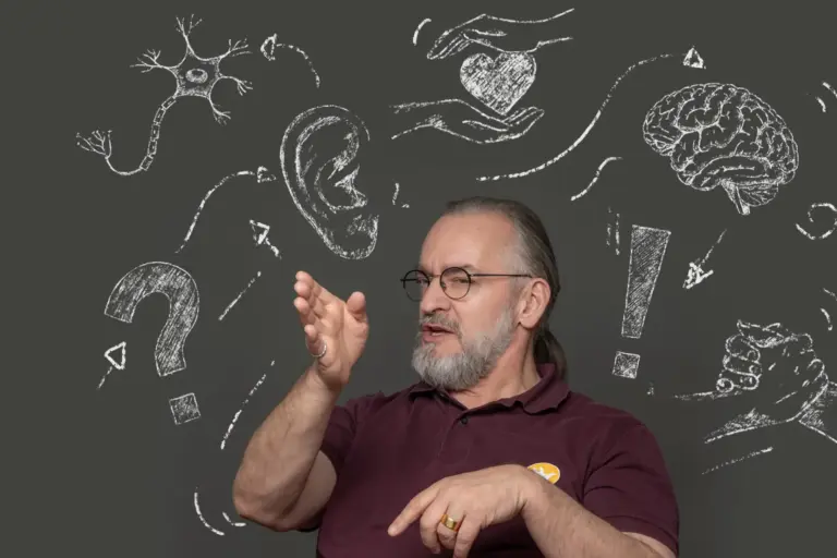 Ein Mann der mit seinen Händen gestikuliert und um den Kreidemotive schwirren