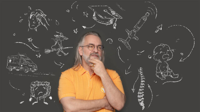 Ein Bild von Ralph Kaufmann der sich nachdenklich ins Gesicht fasst, während er vor einer Kreidemotiv Wand sitzt