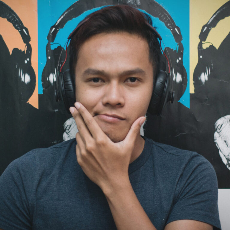 Ein Mann mit Headset und im Hintergrund hängt ein Bild mit kopfhörertragenden Affen.